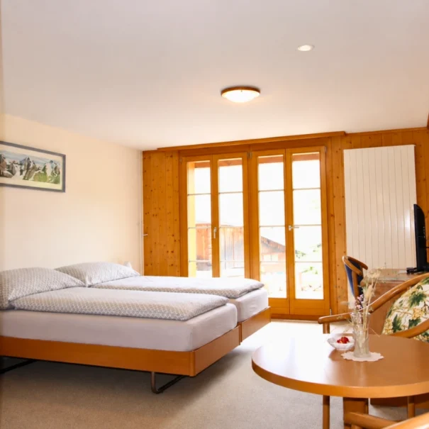 Helles, gemütliches Doppelzimmer im Hotel Waldrand Isenfluh mit Balkon und Bergpanorama.