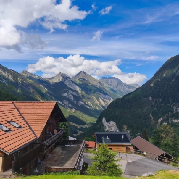 Blick auf das Bergdorf Isenfluh vor der majestätischen Jungfrau-Kulisse mit einer Person im Vordergrund.